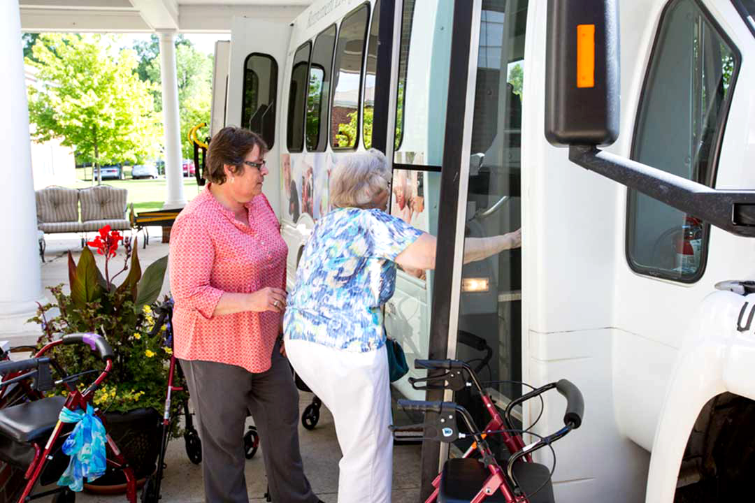 Staff assisting resident boarding a transport vehicle