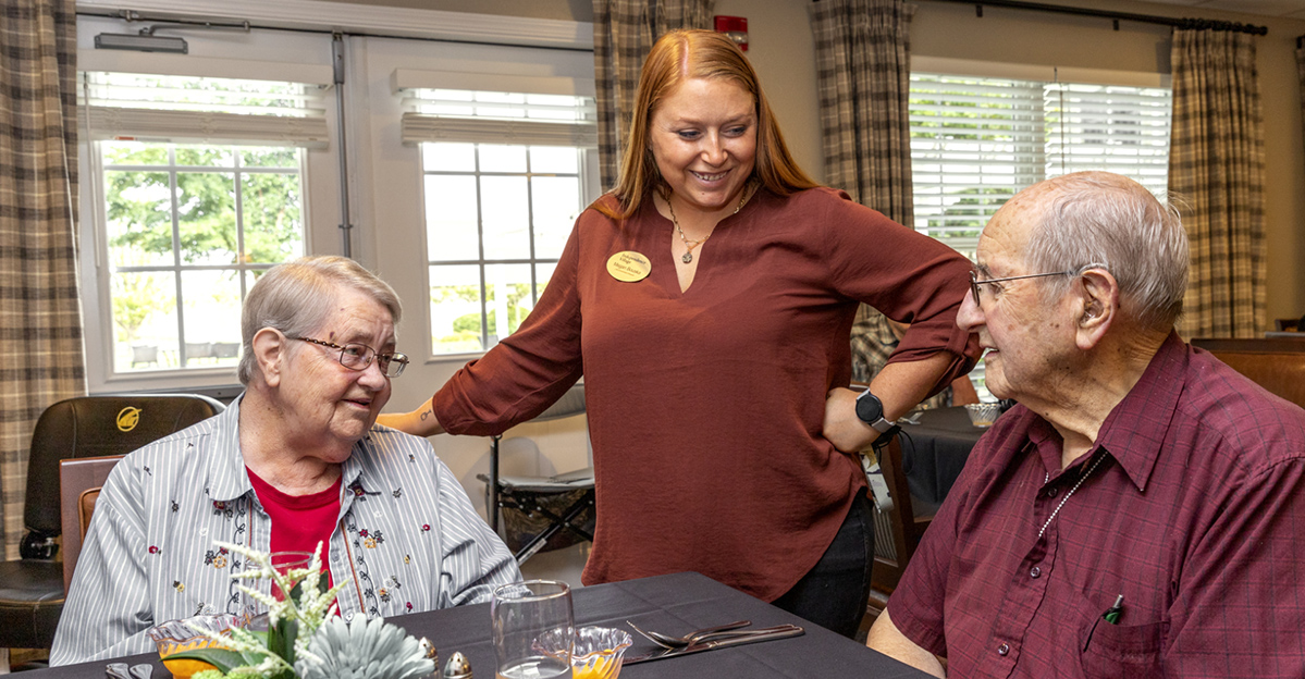 Residents enjoying a meal with staff in the dining room