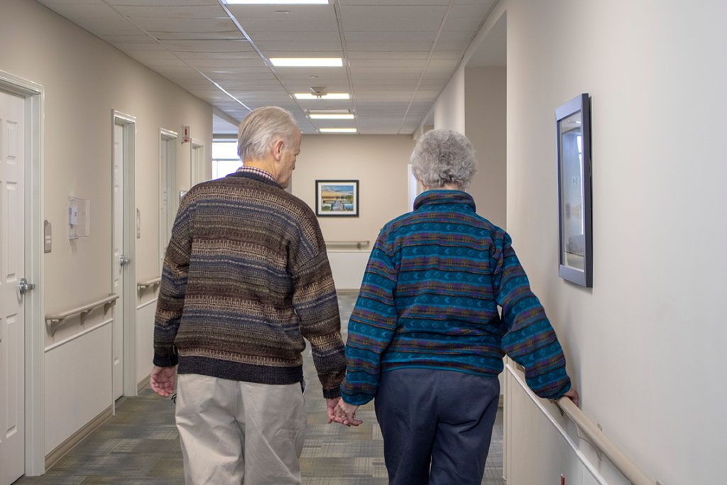 Elderly couple walking hand in hand in a hallway