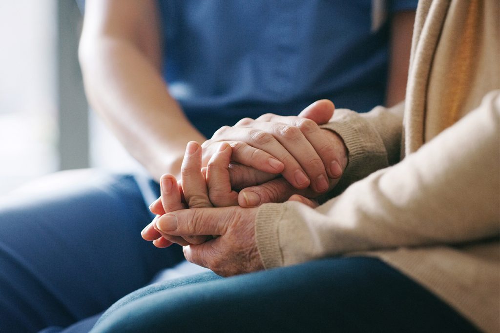Close-up of hands of a caregiver and resident in a caring moment