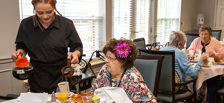 Staff serving food to residents in a dining room