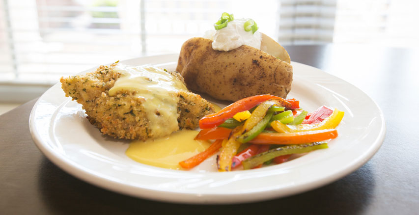 Plate of baked chicken with vegetables and a potato