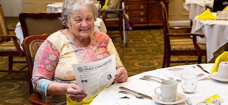 Resident reading a newspaper in a dining area