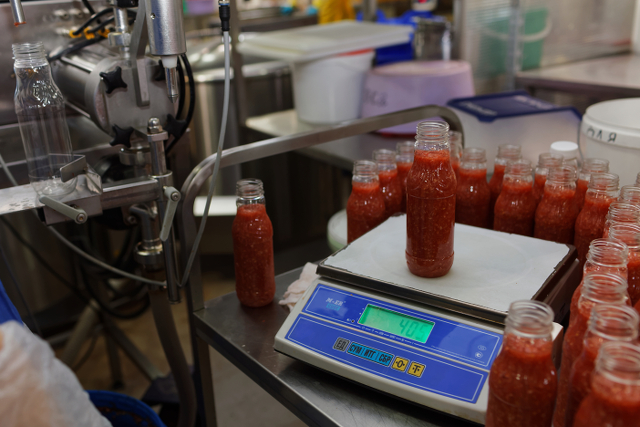 Bottles being filled with sauce in a kitchen