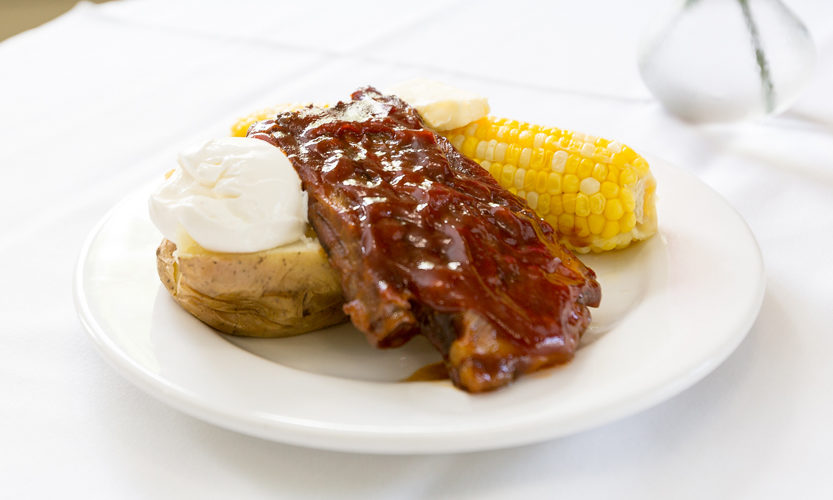 Plate of ribs, corn, and potato with sour cream