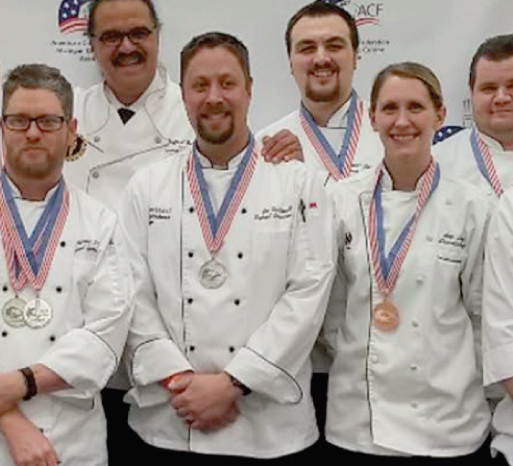 Chefs displaying medals at a culinary competition