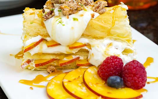 A plated dessert with fruits and cream