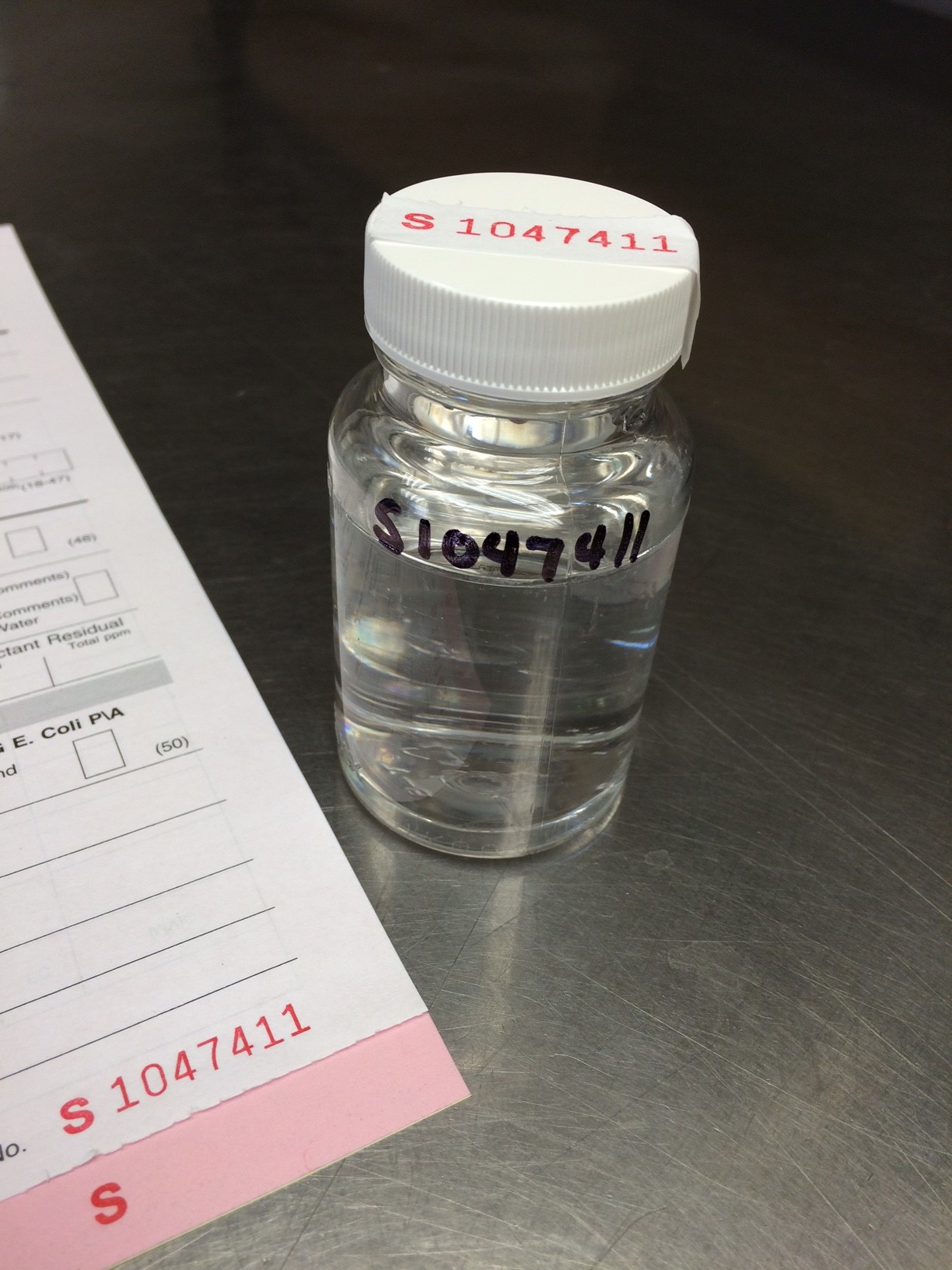 A clear bottle with a label and paperwork