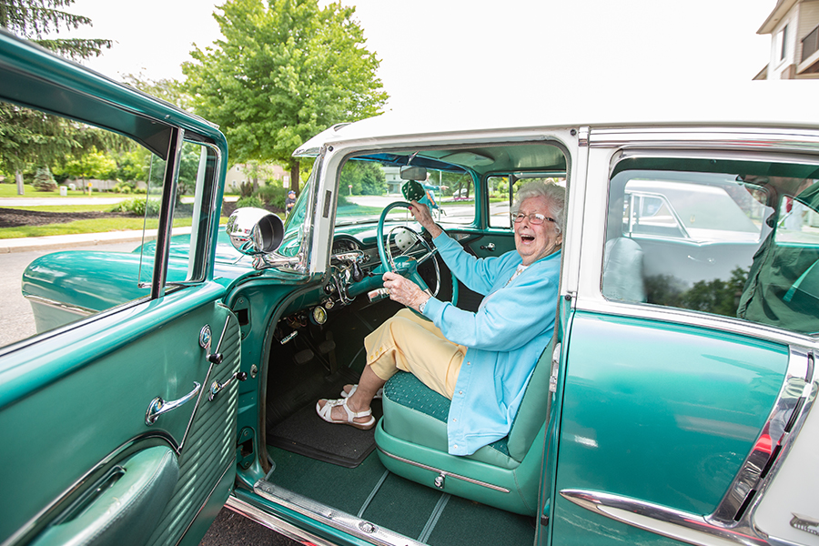 Resident smiling inside a vintage car.
