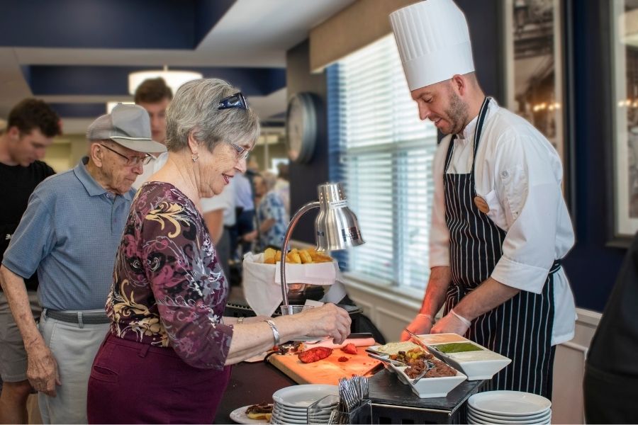 Resident interacting with a chef at a food service station