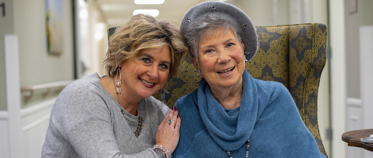 Resident and staff member posing together in a hallway