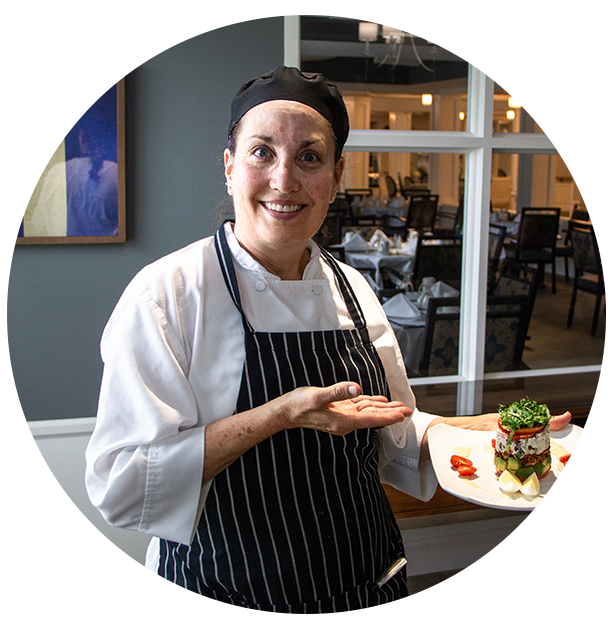 Chef presenting a beautifully plated dish in the dining area