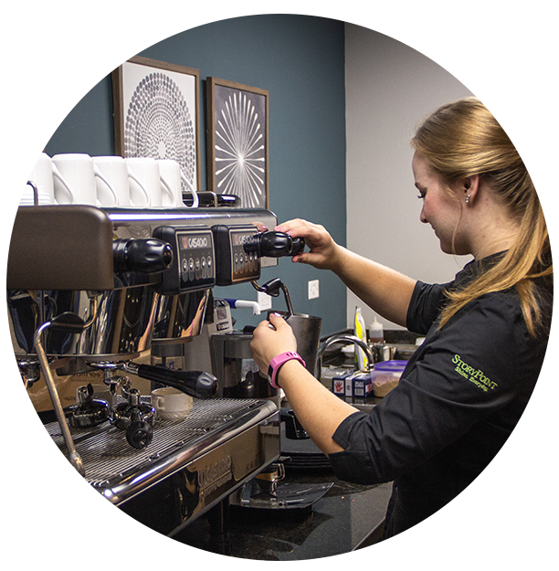 Staff member operating a coffee machine in a cafe setting
