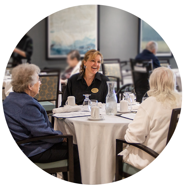 Residents enjoying a meal with a staff member in a dining area