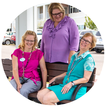 Three staff members laughing on a bench