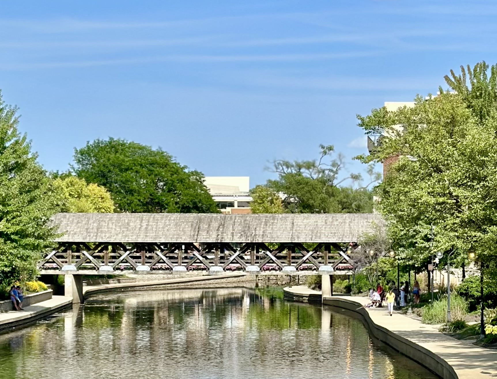 A scenic view of a covered bridge by a tranquil waterway
