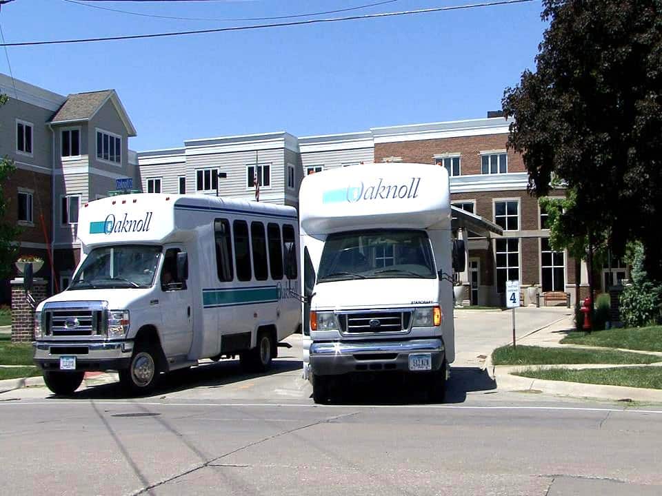 Two facility transport vans parked outside