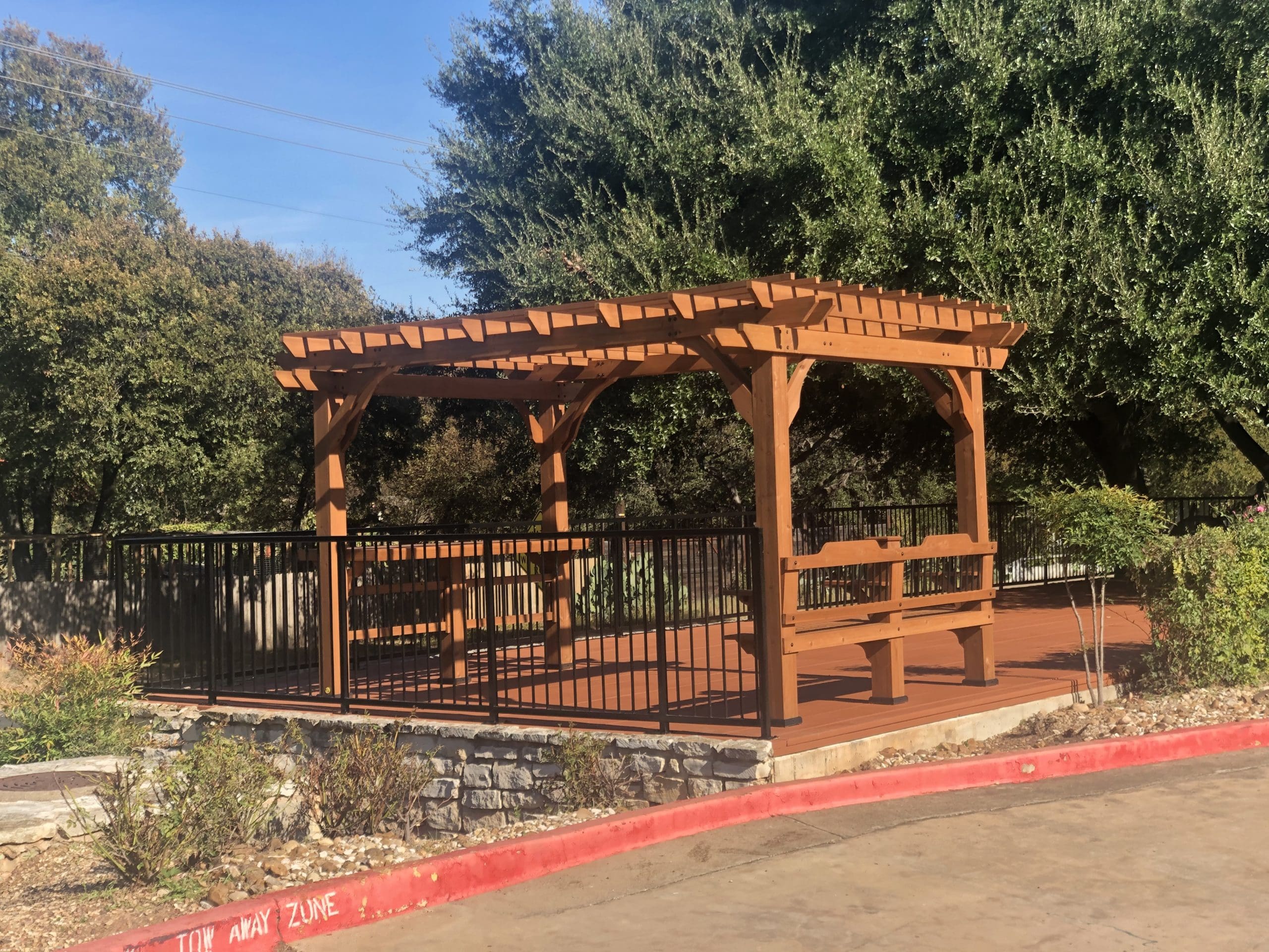 Outdoor pergola area with benches and greenery