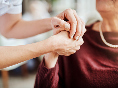 Close-up of caregiver holding a resident's hand