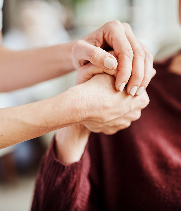 A caregiver holding a resident's hand in a caring gesture