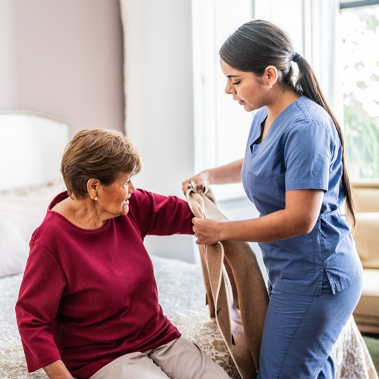 Caregiver assisting a resident with a sweater