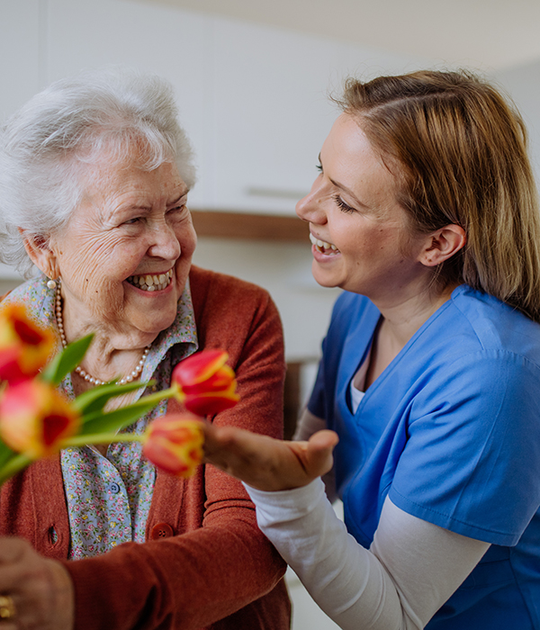 A smiling resident and staff member sharing flowers