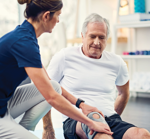 Therapist assisting a senior man with knee rehabilitation