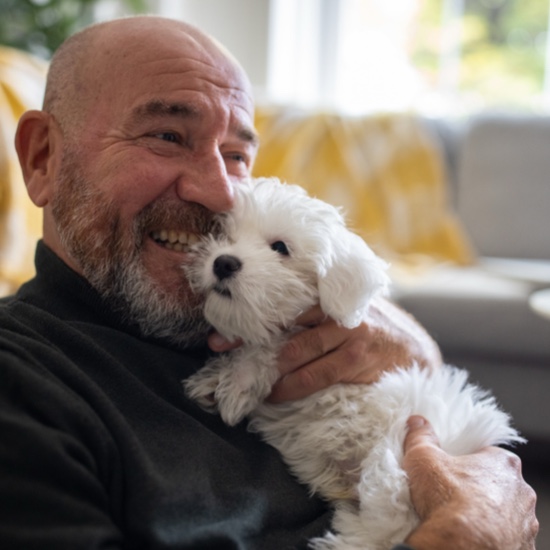 Man smiling while holding a small puppy