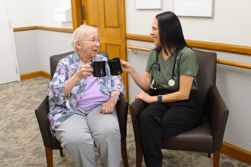 Resident and nurse sharing a moment with coffee mugs in a common area