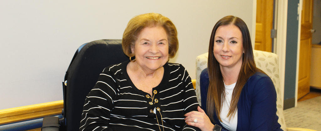 Resident and staff member smiling together in a common area