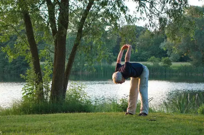 Senior stretching near a peaceful lake
