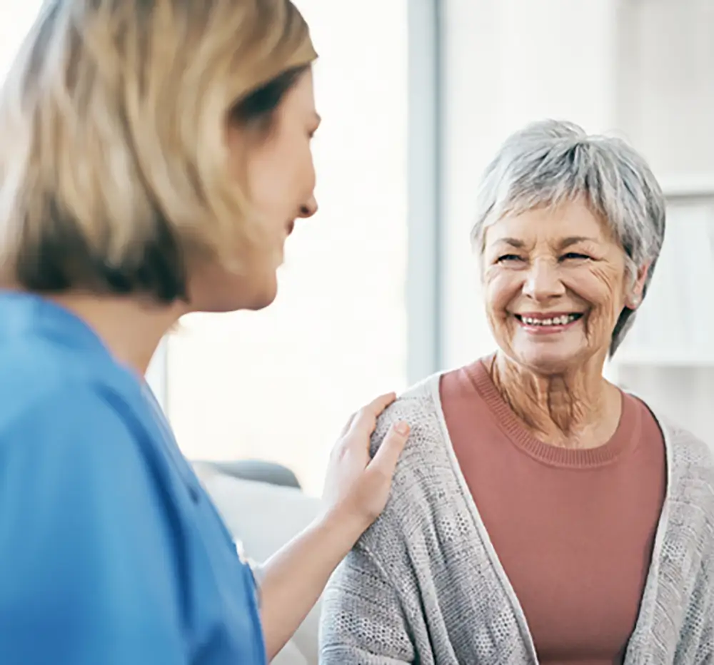 A senior resident smiling with a caregiver