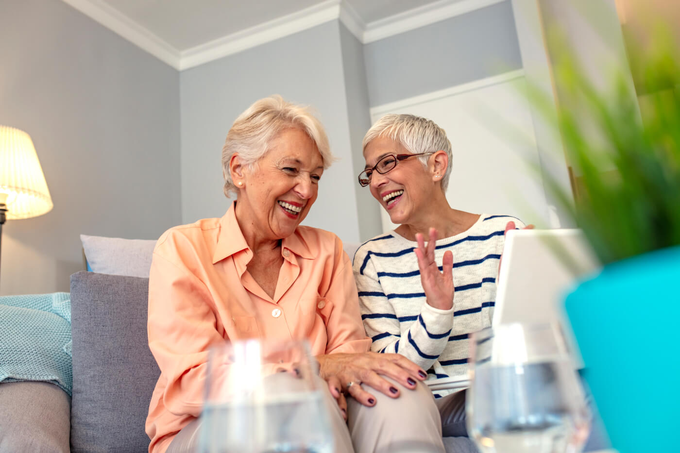 Two elderly women laughing together in a cozy indoor setting