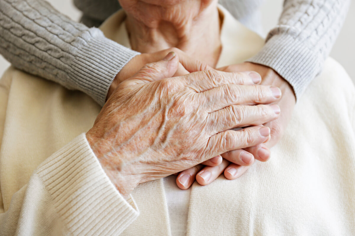 Close-up of an elderly person's hands with younger hands resting on top