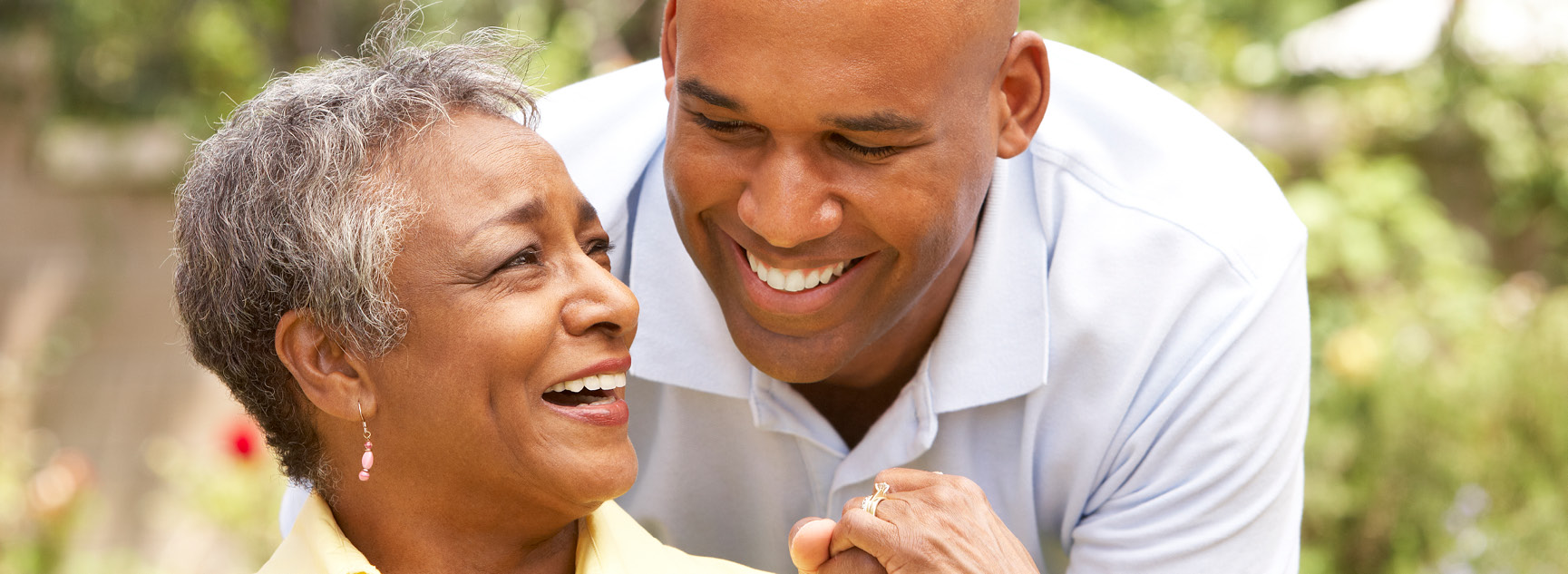 A resident and staff member smiling outdoors in a garden