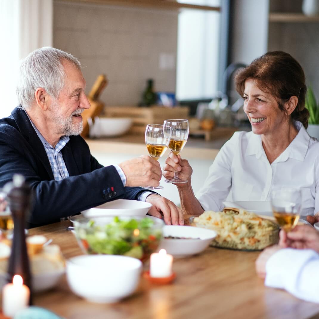 Residents enjoying a meal and toasting at a dining table