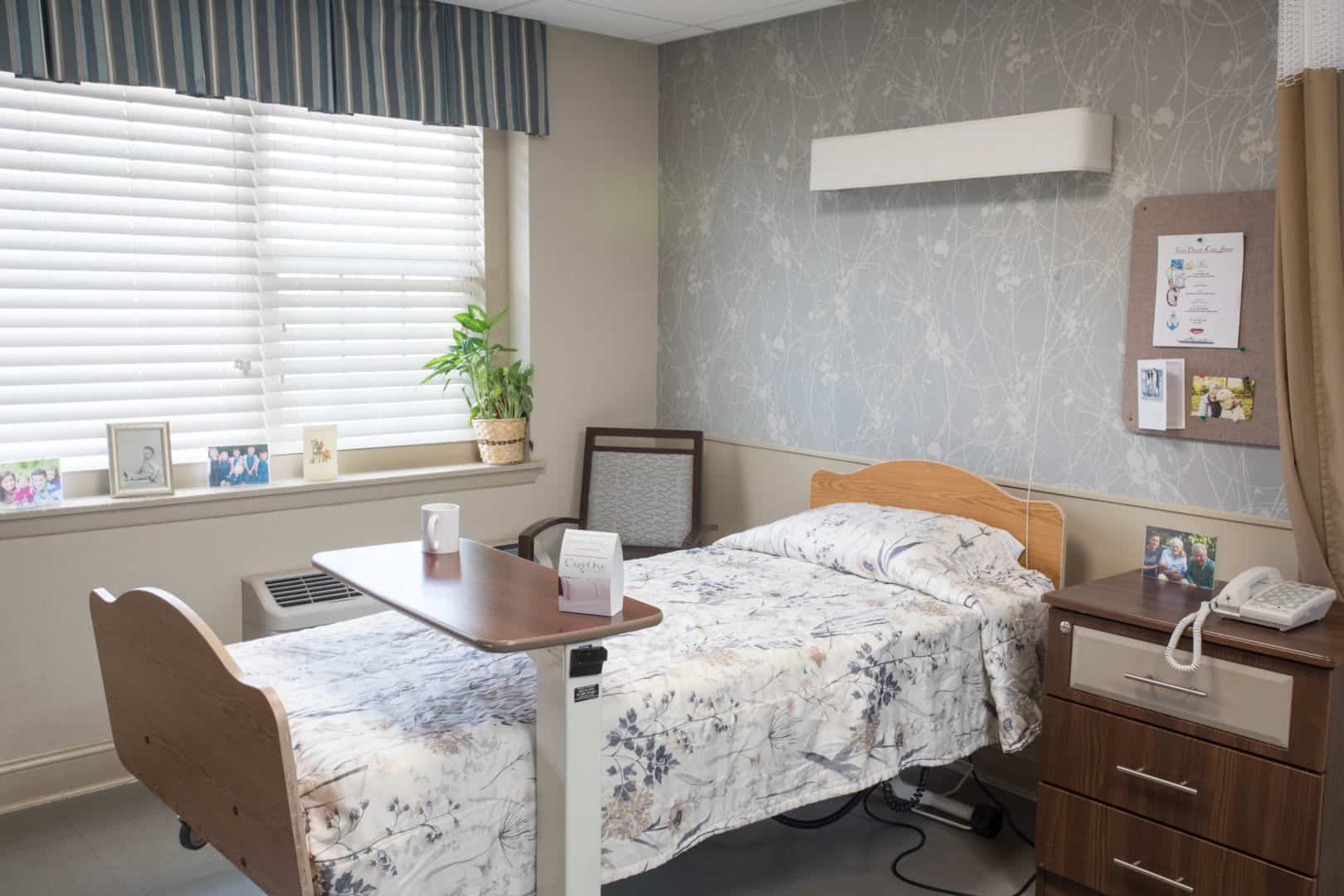 Brightly furnished resident room with bedside table and window