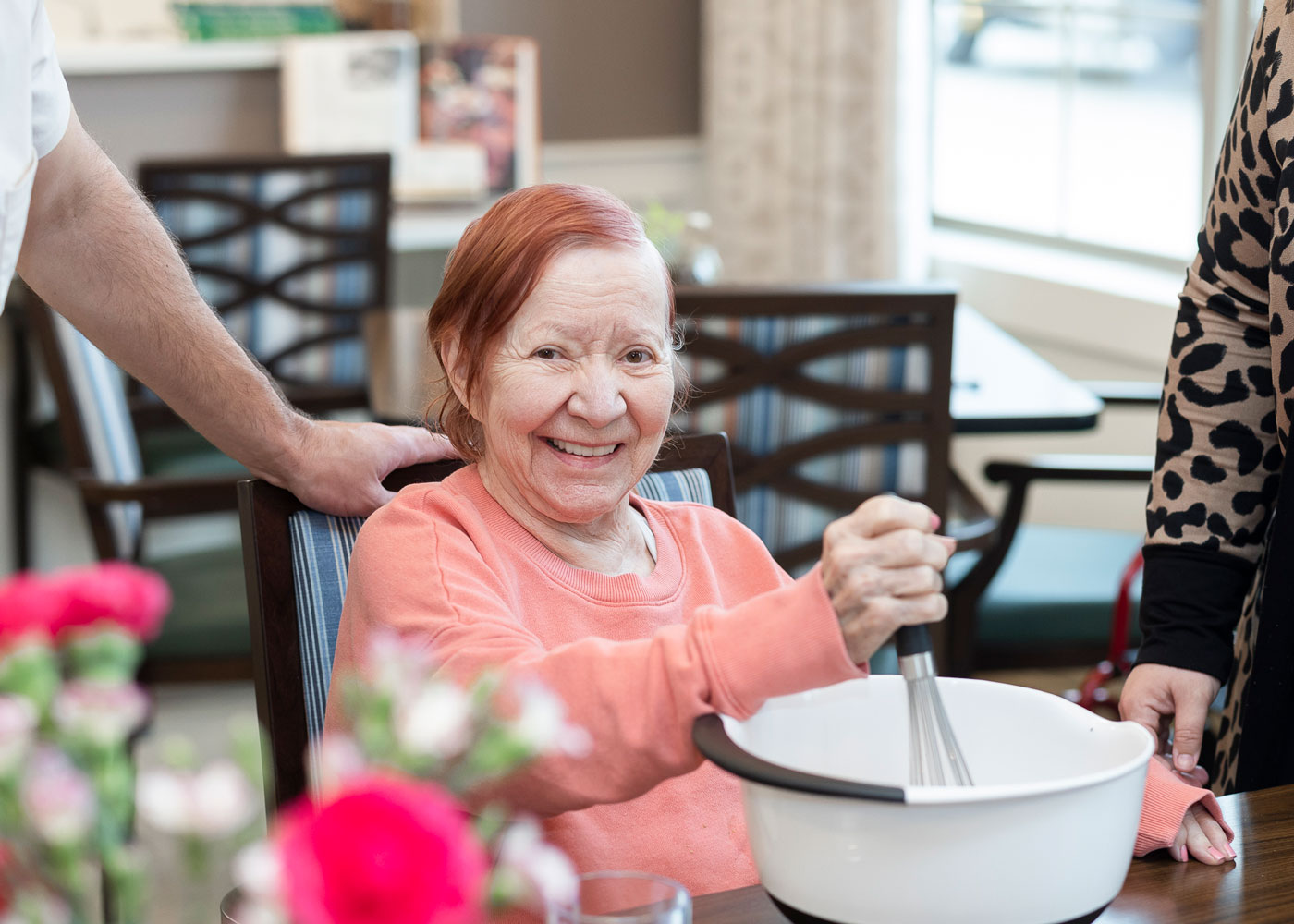 A resident smiling while mixing ingredients in a bowl