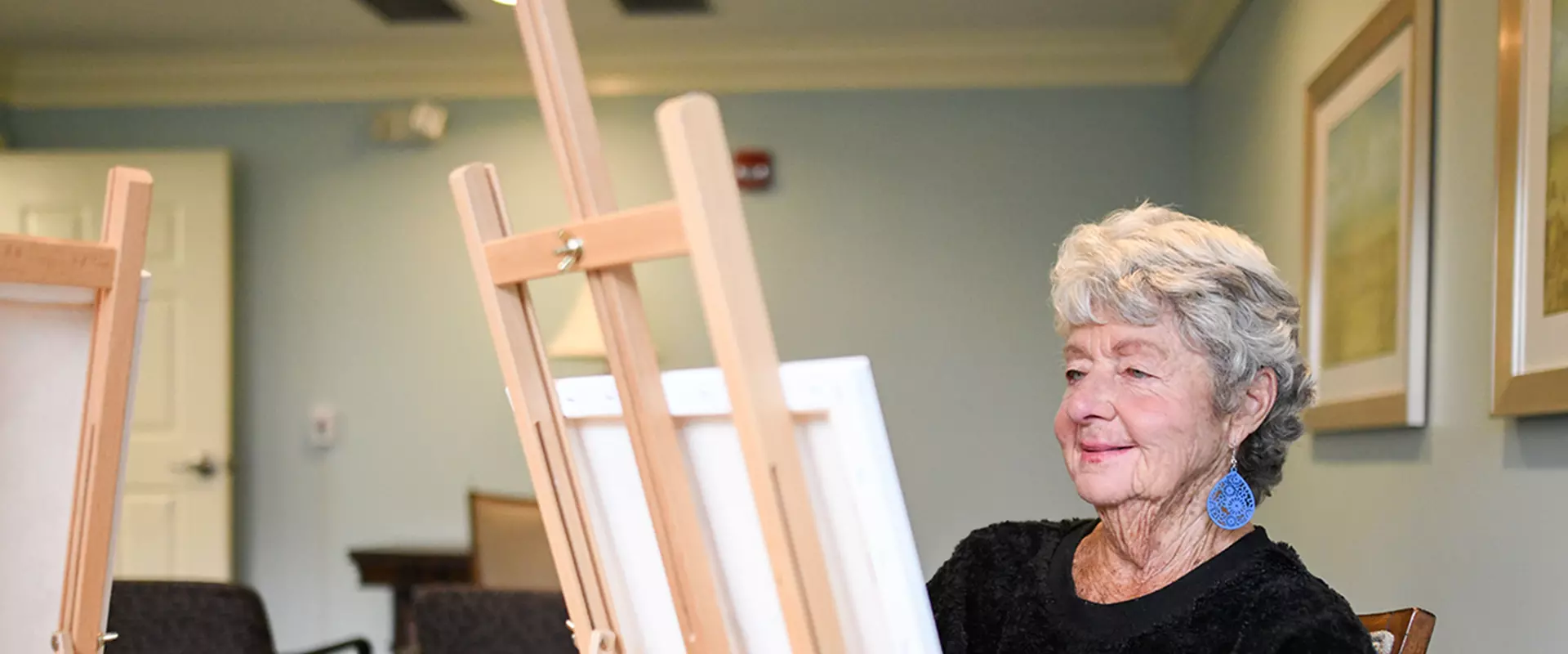 Resident painting at an easel in an activity room