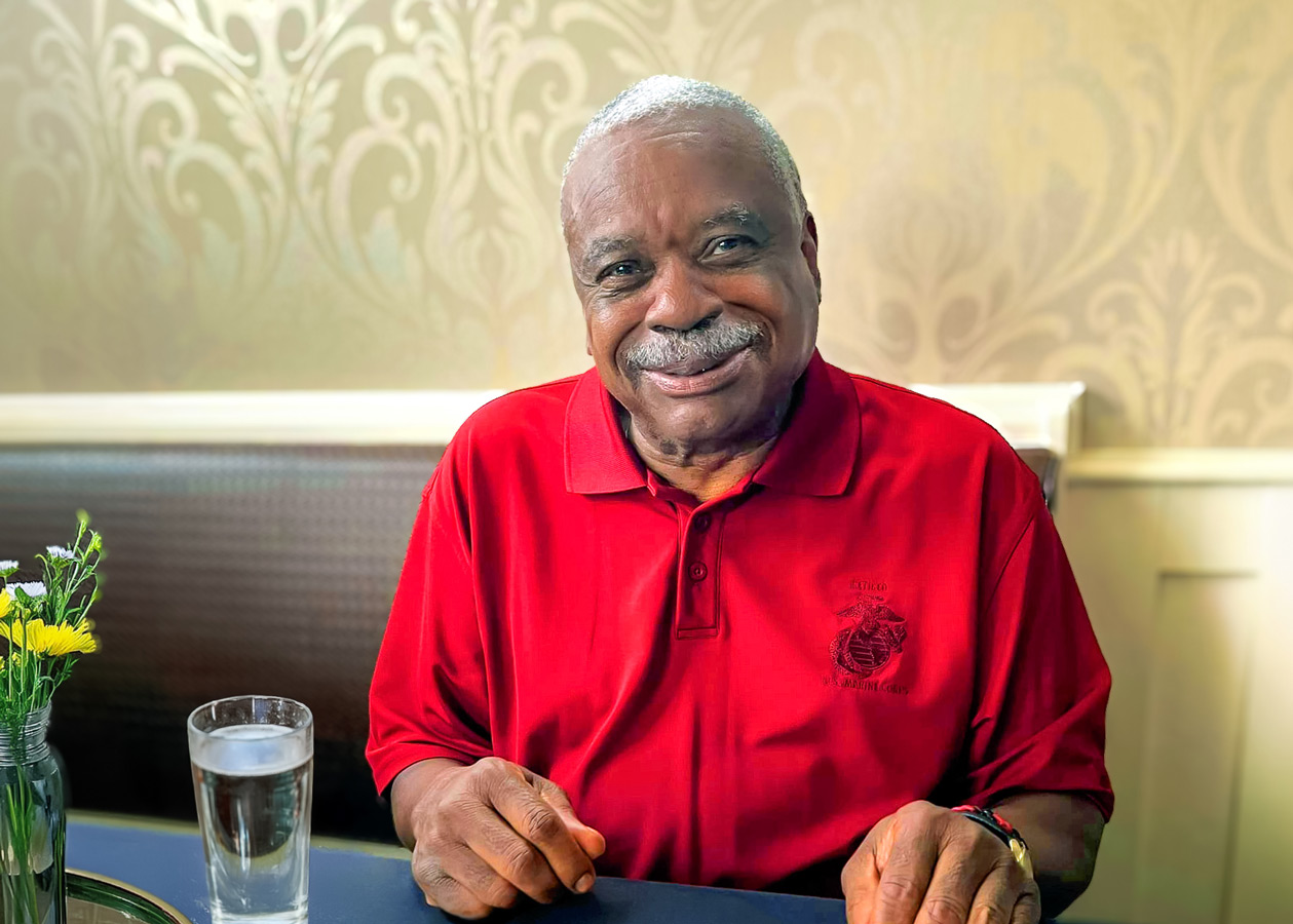 Resident smiling in a dining area with a drink