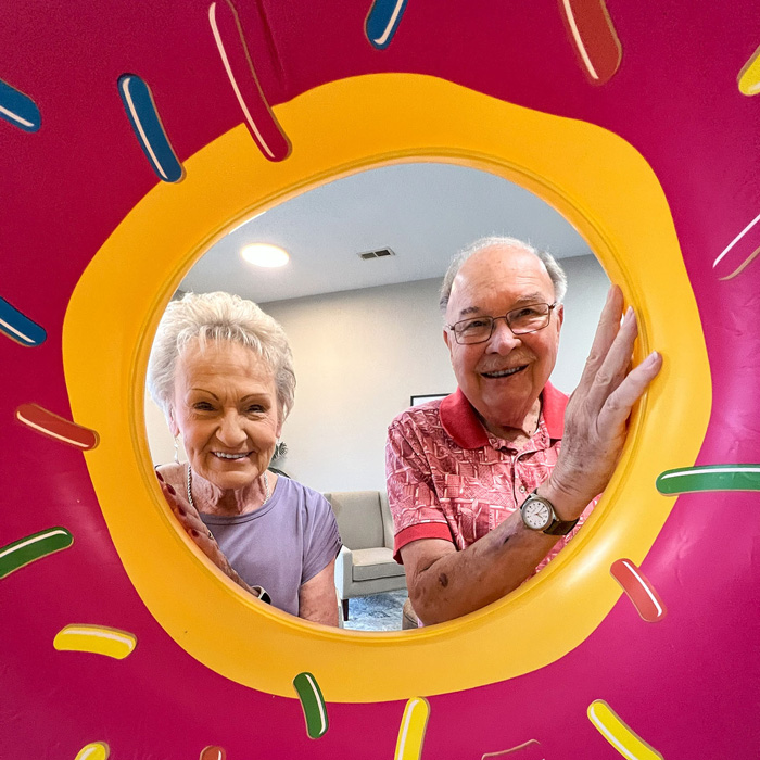 Two smiling seniors posing with a colorful inflatable
