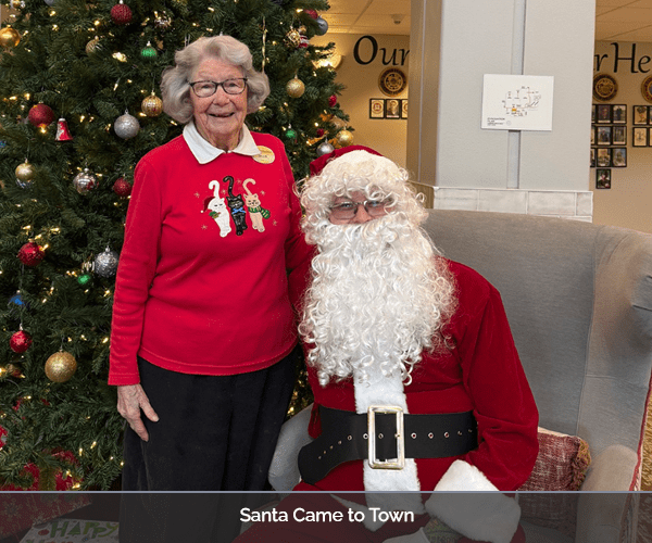 Resident posing with Santa in the lobby during a holiday event