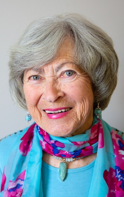 A smiling elderly woman with gray hair and a colorful scarf