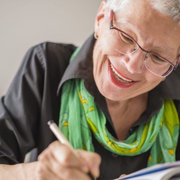 Woman smiling while writing in a notebook
