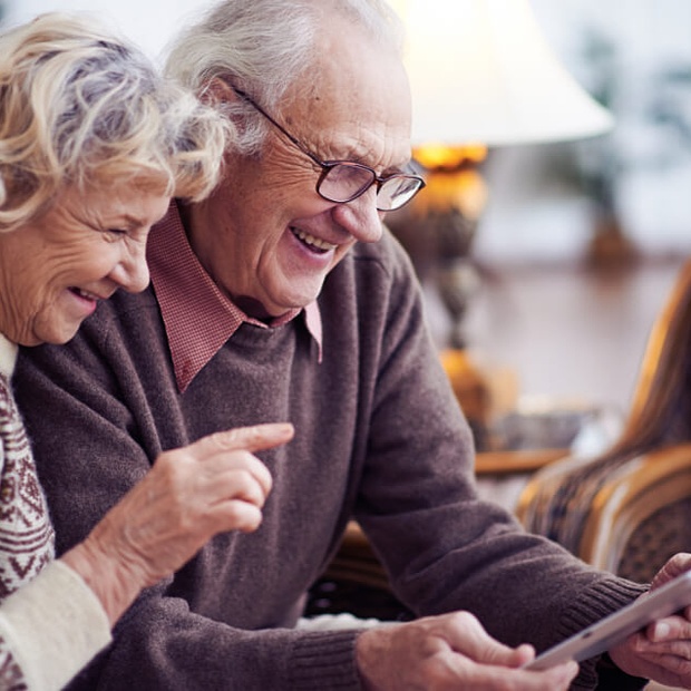 Two seniors smiling and engaging with a tablet