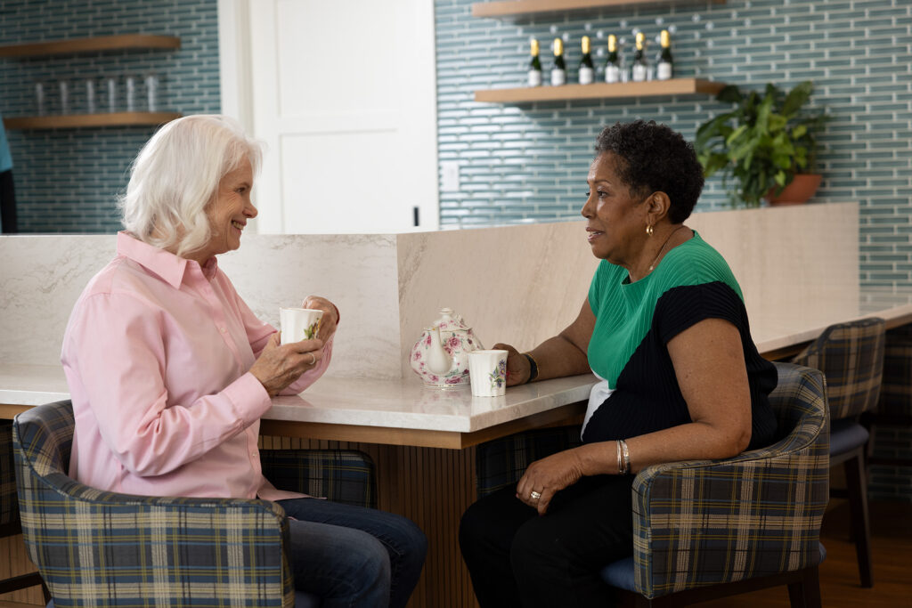Two residents chatting over tea in a common area