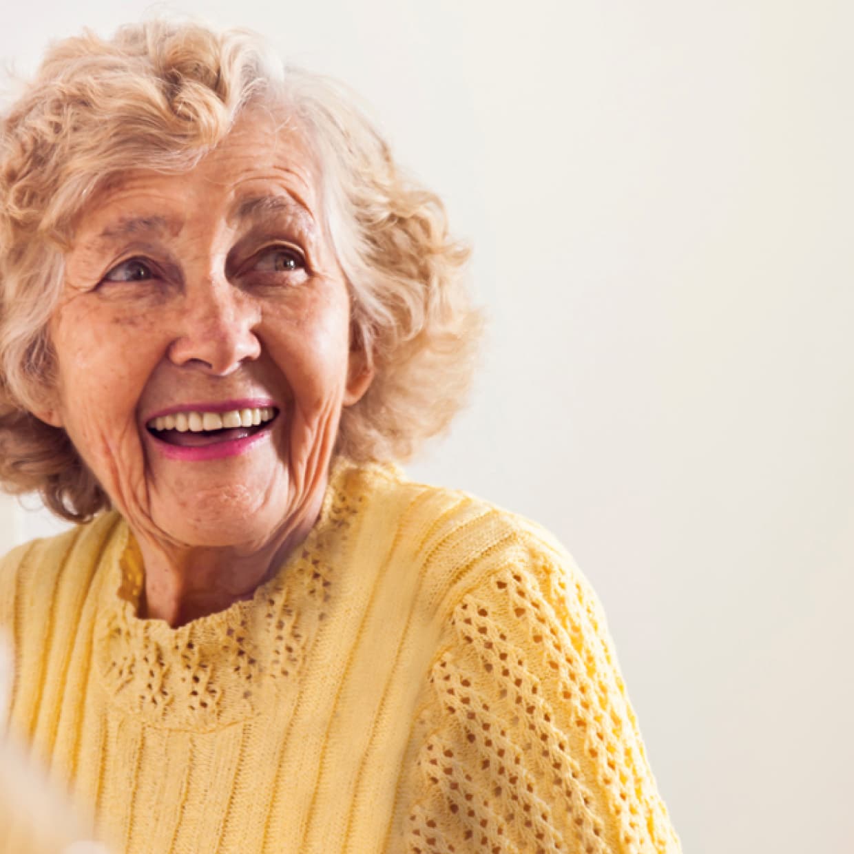 A senior woman smiling warmly in a bright room