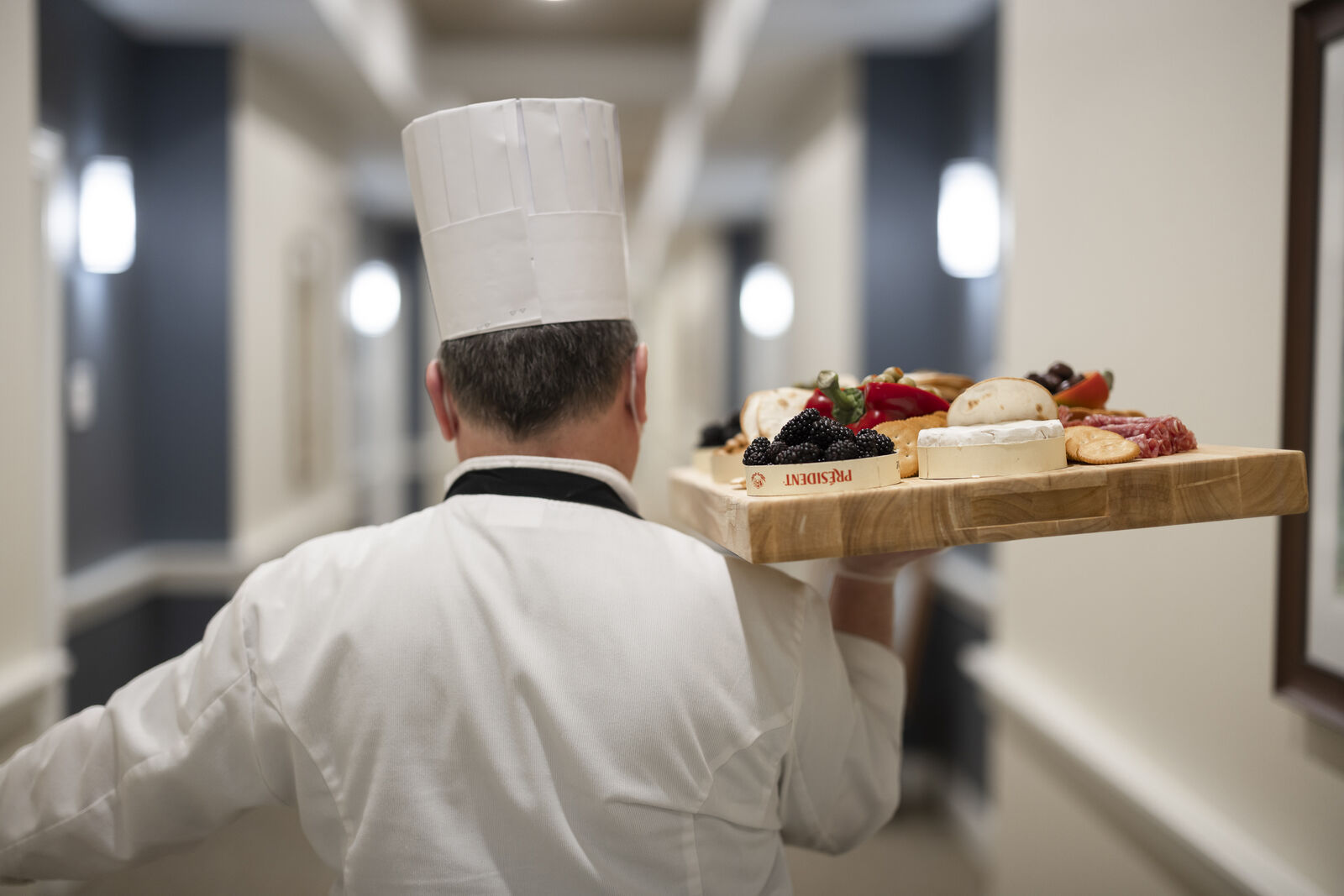 Chef carrying a platter of gourmet food in a corridor