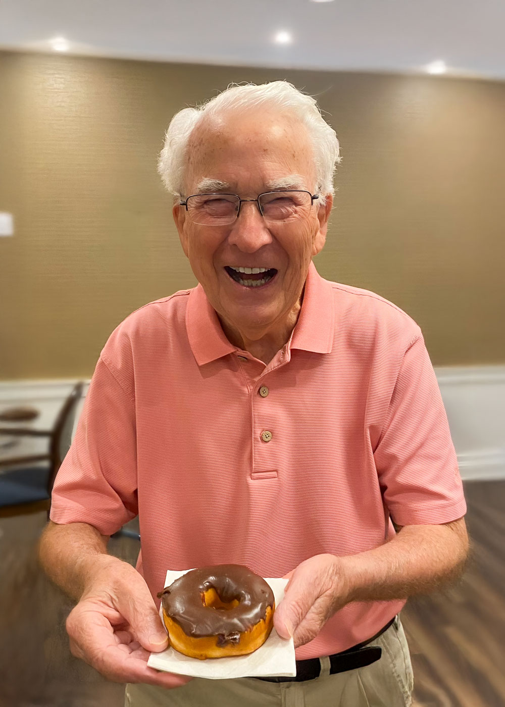 Smiling resident holding a donut in the common area