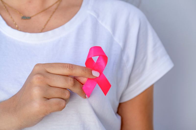 A person holding a pink awareness ribbon